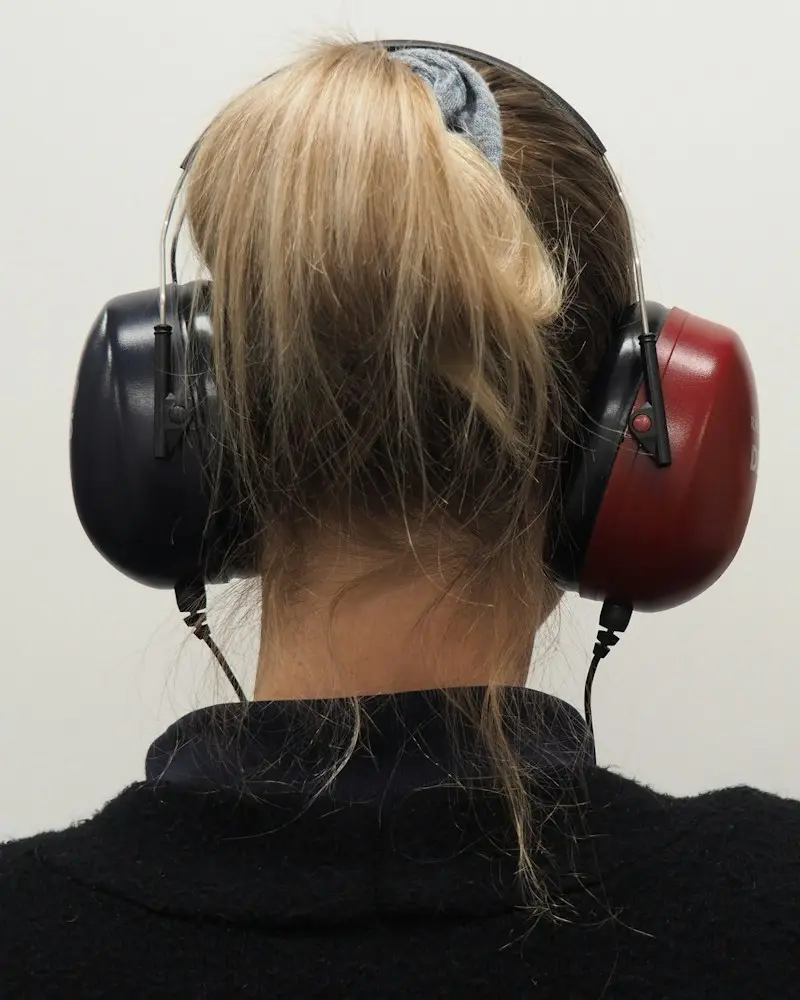 Paciente con auriculares durante una audiometría tonal en cabina insonorizada