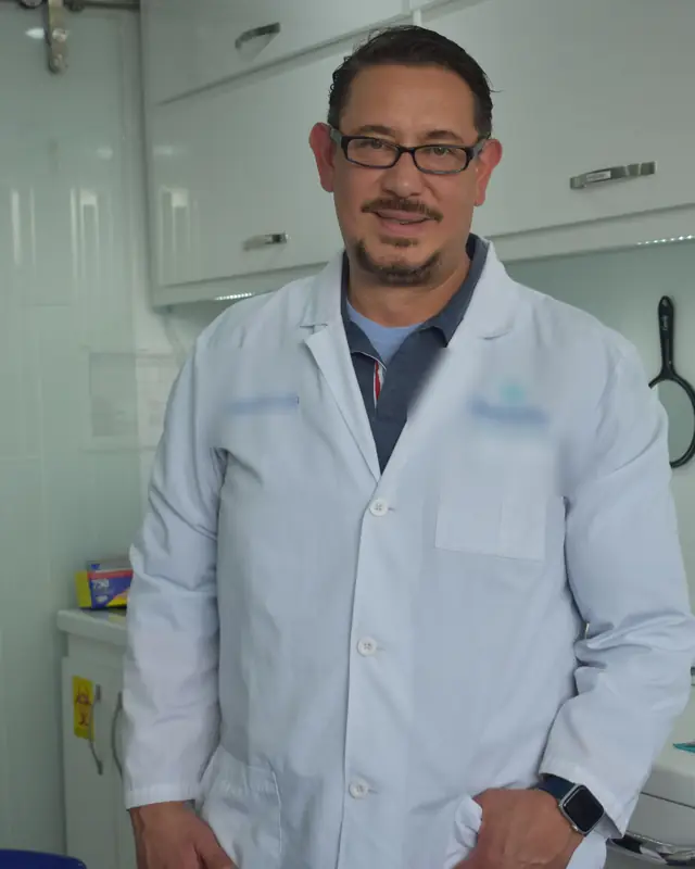 Dentista que se dedica a la cirugía oral, con bata blanca, sonriendo