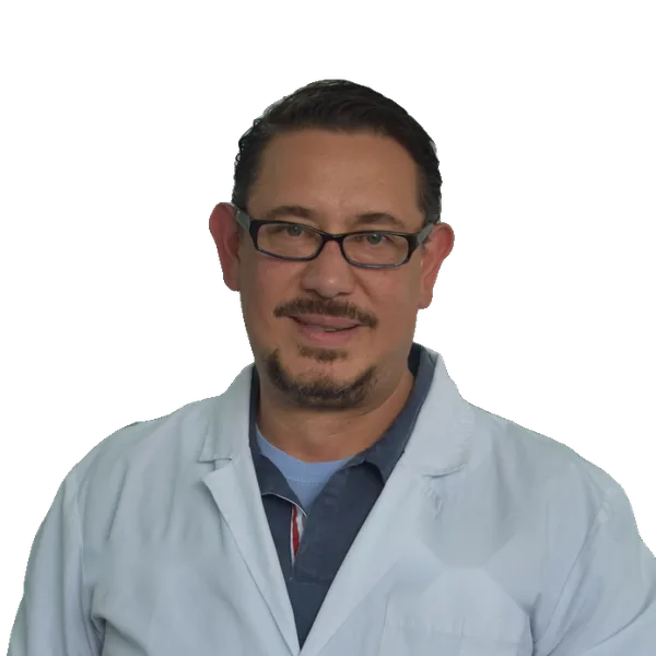 Dr. Javier Molina, cirujano oral de Clínica Velia, con bata blanca y gafas