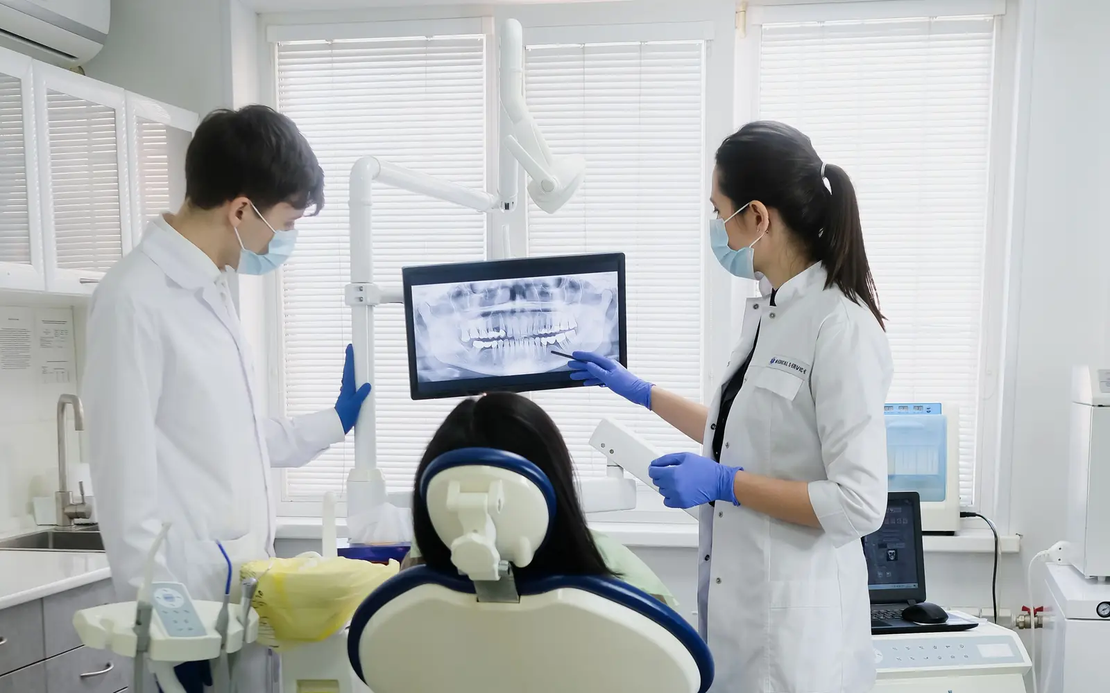 Dos dentistas de la clínica revisan una radiografía en la pantalla junto al sillón para preparar el plan