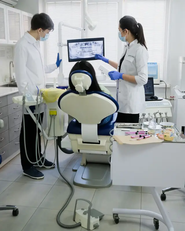 Dos dentistas revisan una radiografía en la pantalla del gabinete