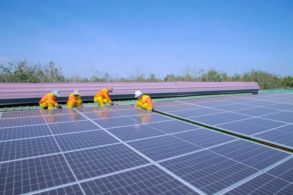 Dos instaladores con equipo de protección colocando placas solares en un tejado