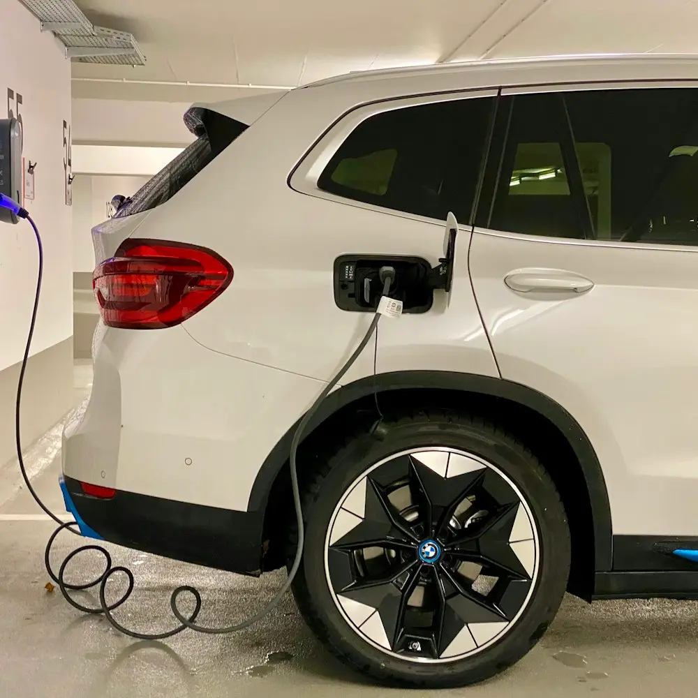 Coche eléctrico cargando en un punto de recarga de pared en un garaje comunitario