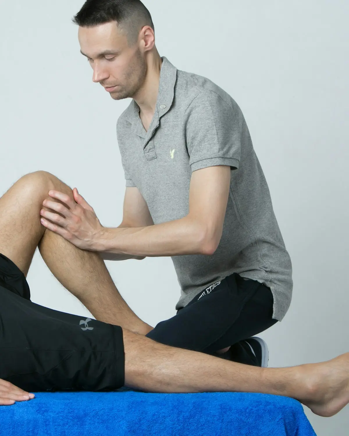 Traumatólogo explorando la rodilla de un paciente en la consulta